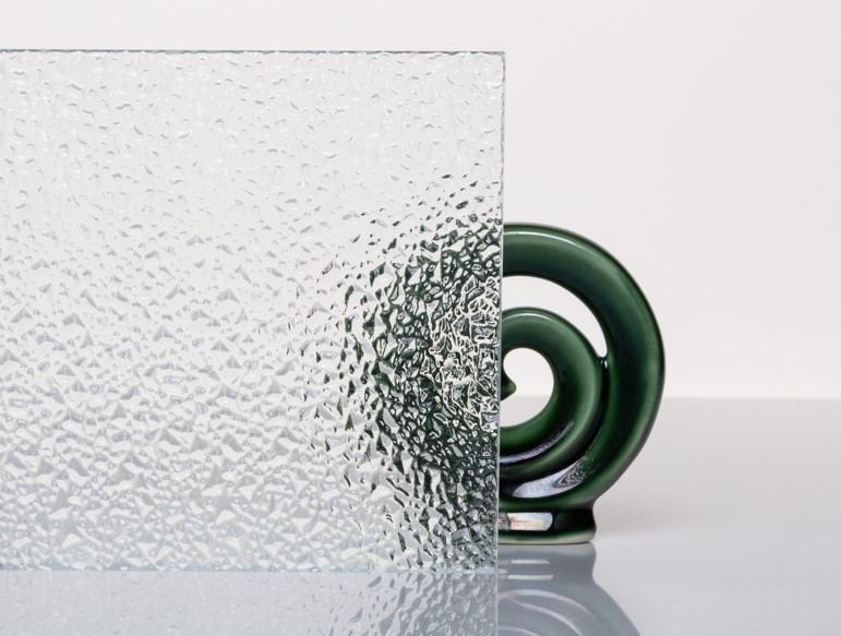 Cropped images of textured etched glass with a stunning glass koru design in the background.